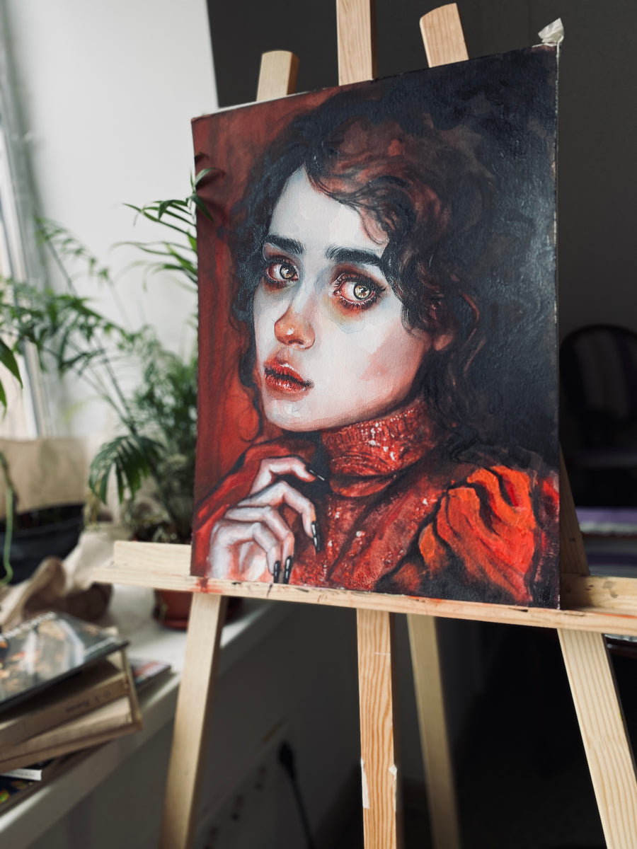 Painting of a woman with red hair on an easel indoors